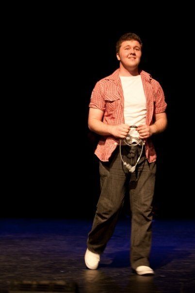 Tristan performing on stage in a community musical theatre production